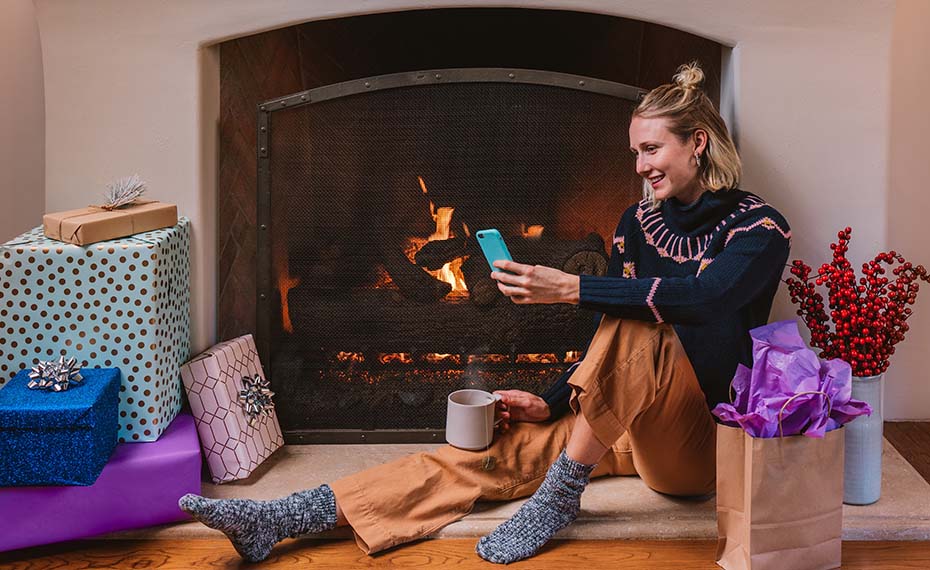 person looking at phone in front of fireplace
